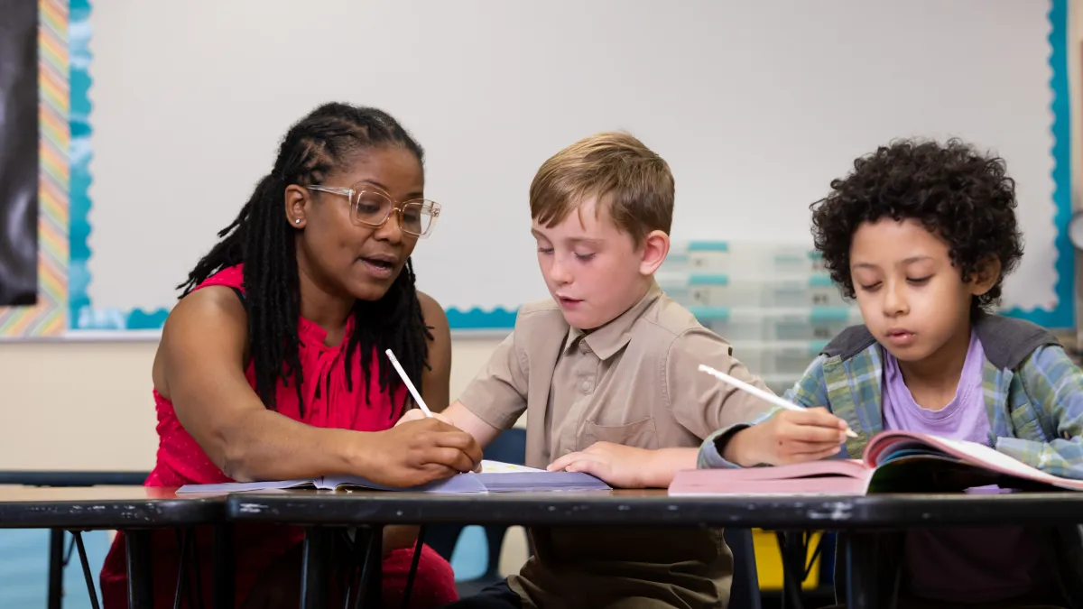 Teacher helping two students with school work