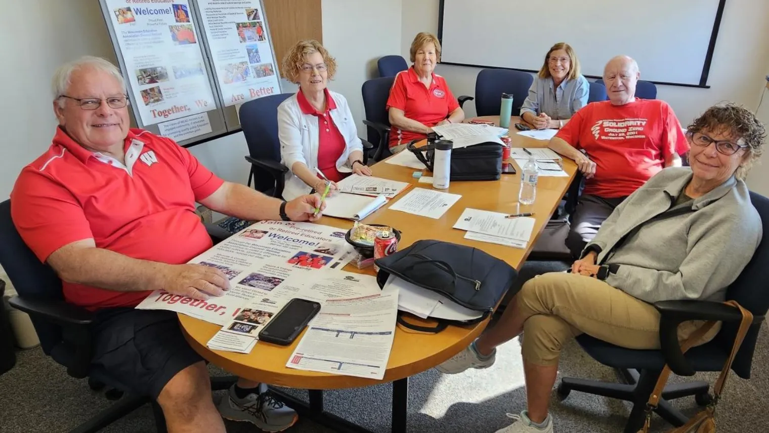 WEAC Retired membership committee sitting around a desk in a conference room all wearing red shirts