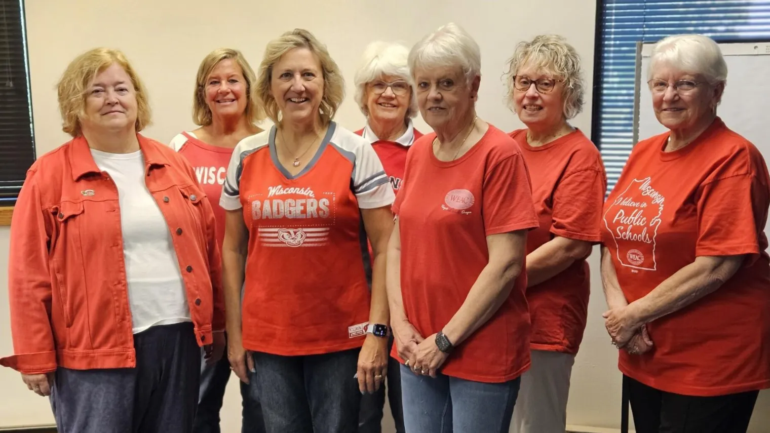 WEAC Retired PR committee standing in office and they are all wearing red shirts.