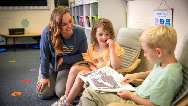 Brailey Kerber listens to a student reading aloud in classroom library