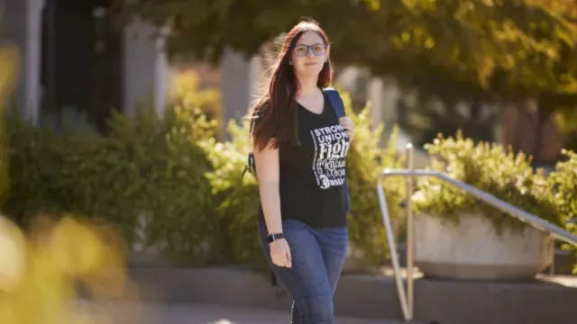 Aspiring educators student standing outside carrying backup