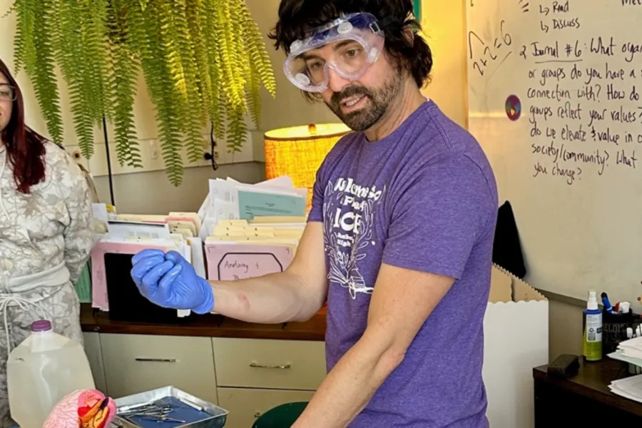 Science teacher giving demonstration while wearing protective goggles and gloves